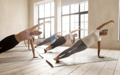 Een groep mensen beoefent yoga in een yogastudio. Iedereen staat in dezelfde yogahouding, op diens eigen matje