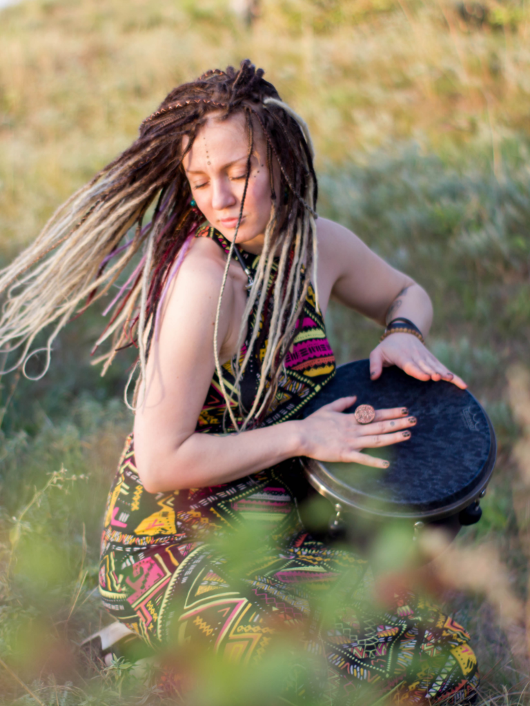 Een vrouw met dreadlocks danst terwijl ze muziek maakt op een handpan