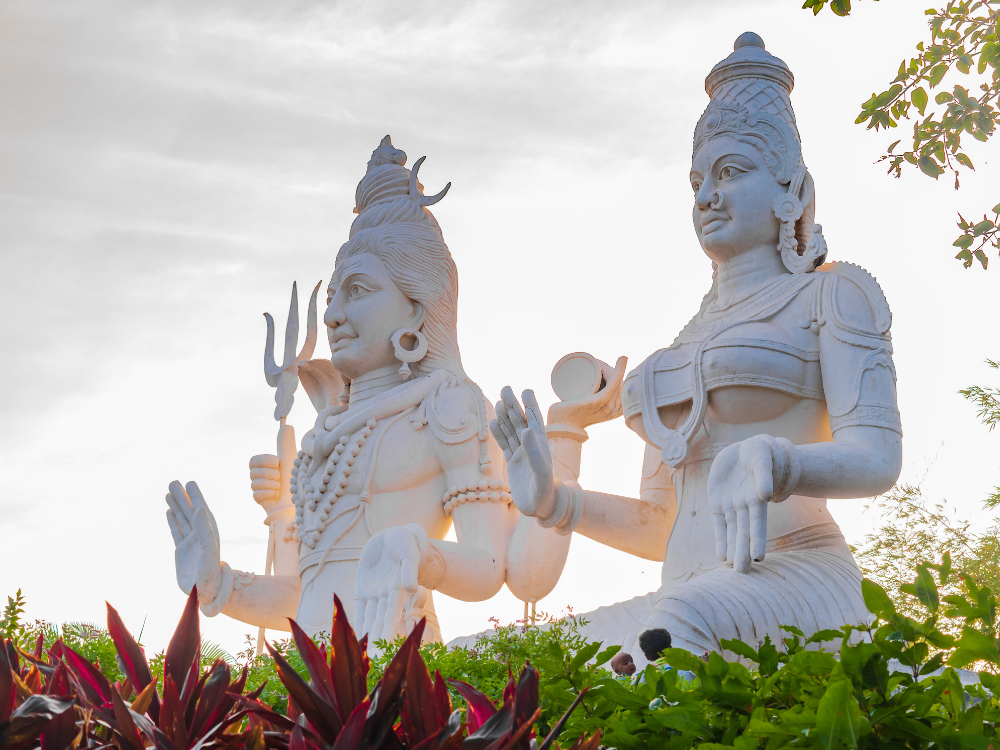 Twee hele grote standbeelden naast elkaar. Links zit Shiva, rechts Parvati.
