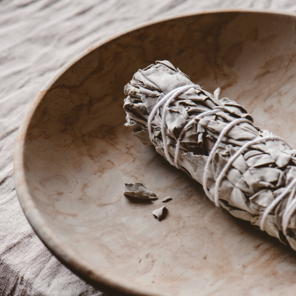 Een witte salie smudge stick in een houten bakje